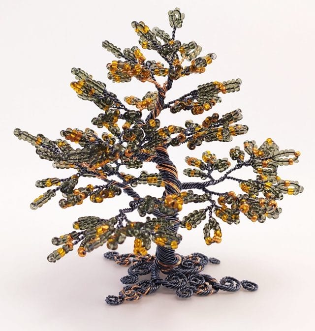 Image shows a twisted metal tree with orange and grey beads.