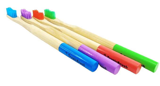 TropicBrush Bamboo Toothbrushes. Image shows 4 toothbrushes lined up. There's a blue, purple, red and green toothbrush.