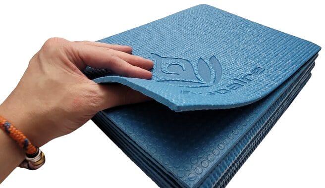 Image shows my left hand squeezing the mat to indicate the thickness of the yoga mat.