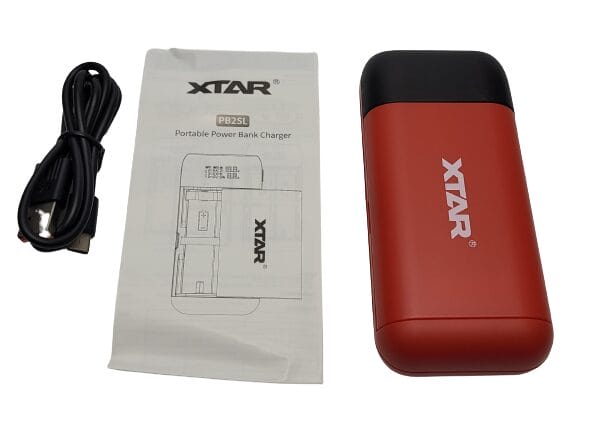 Image shows the included contents of the XTAR PB2SL Battery Charger. Contents are laid out in a line.