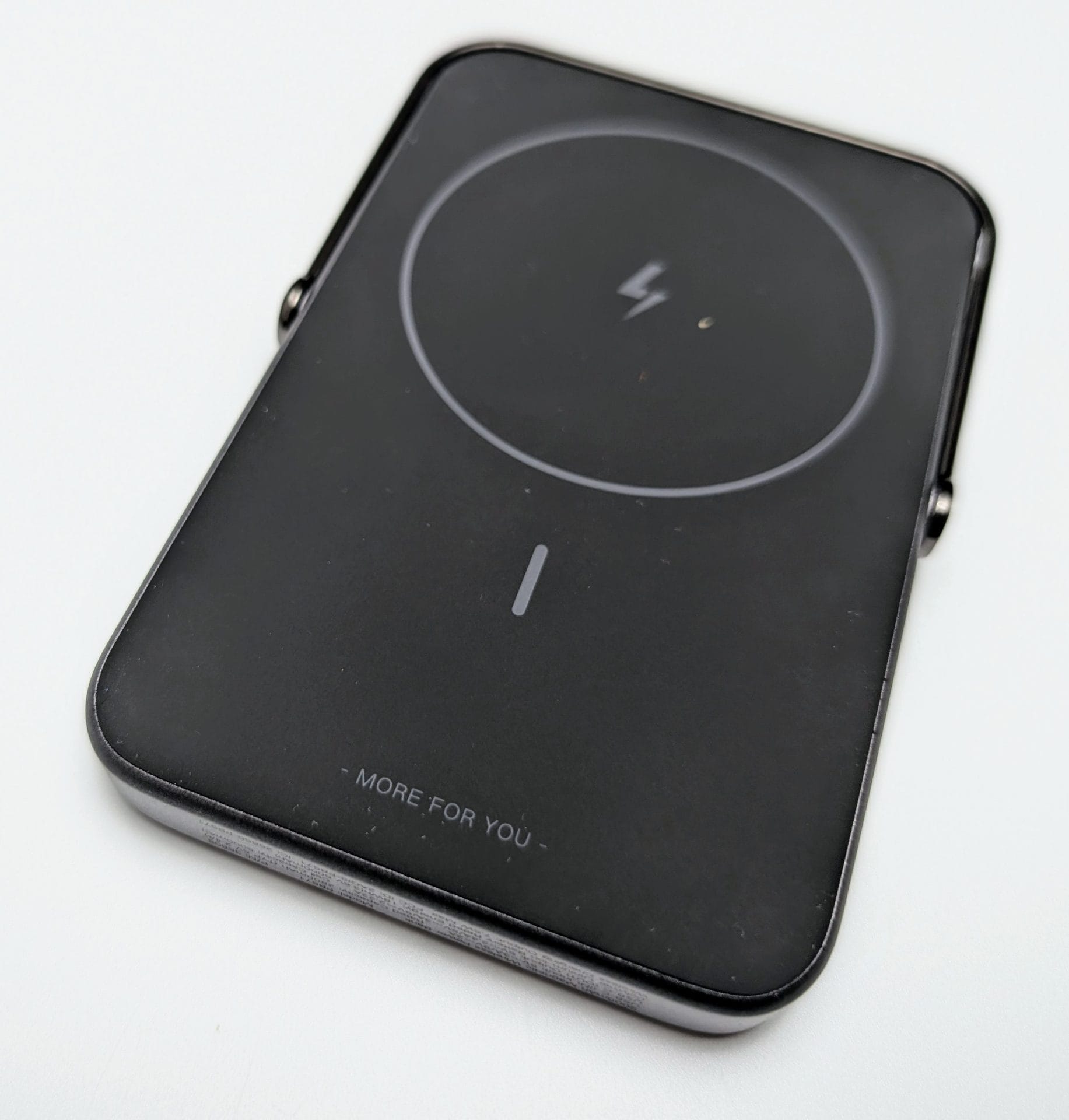 A sleek, black UGREEN Uno Magnetic Wireless Power charger with a circular charging pad featuring a lightning bolt icon in the center. The device has a minimalist design with the phrase 'MORE FOR YOU' etched near the bottom edge. The charger has rounded corners and a smooth, glossy finish.