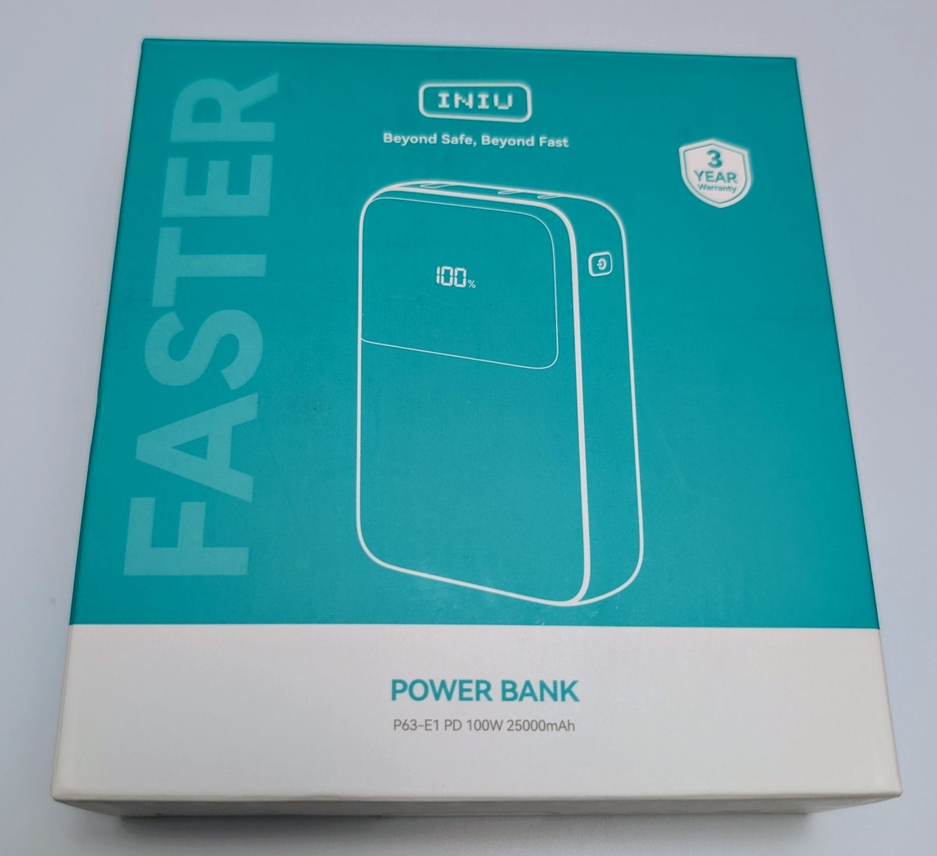 Box of INIU P63-E1 PD 100W 25000mAh Power Bank with a teal and white design. The front of the box features an image of the power bank, which has a digital display showing '100%'. Text on the box reads 'FAST', 'Beyond Safe, Beyond Fast', 'POWER BANK', and '3 YEAR WARRANTY'