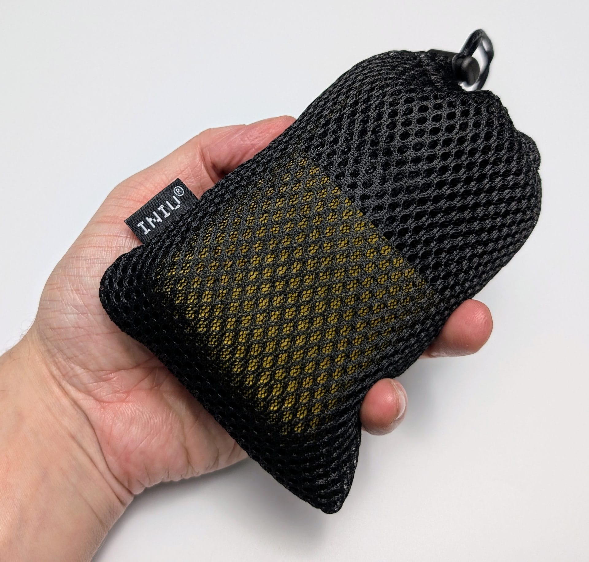 A hand holding a black mesh carrying pouch with a yellow section, branded with the INIU logo. The pouch is partially closed with a drawstring and has a small loop for hanging or attaching.