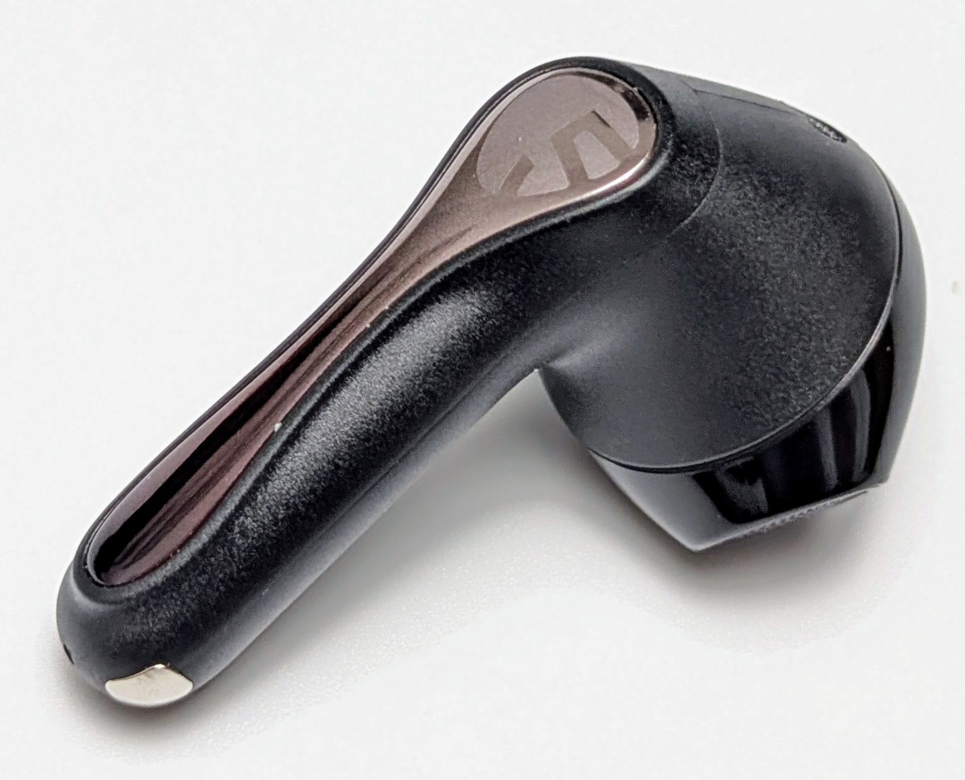 Image of a single SoundPEATS Air5 wireless earbud. The earbud is predominantly black with a sleek, glossy finish. It has a unique, curved design with a metallic accent on the top part, which features a logo that resembles a stylized 'S'. The earbud has a smooth, rounded shape with a small metallic contact point at the end, likely for charging purposes.