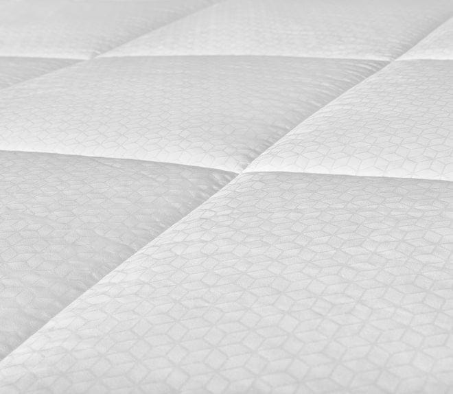 A close-up view of the surface of a white quilted duvet cover with a subtle geometric pattern. The fabric appears soft and smooth with neatly stitched quilted sections.