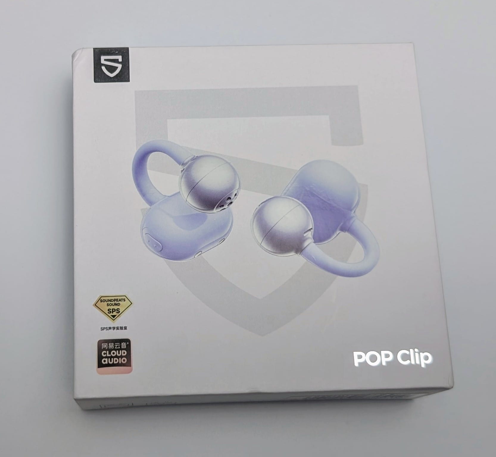 SoundPEATS POP Clip Earbuds A white box packaging for SoundPEATS POP Clip Earbuds features an image of two light purple earbuds with a clip design. The box includes the SoundPEATS logo, a "Cloud Audio" label, and the product name "POP Clip" in white text. A small diamond-shaped badge reads "SPS" in the bottom left corner.