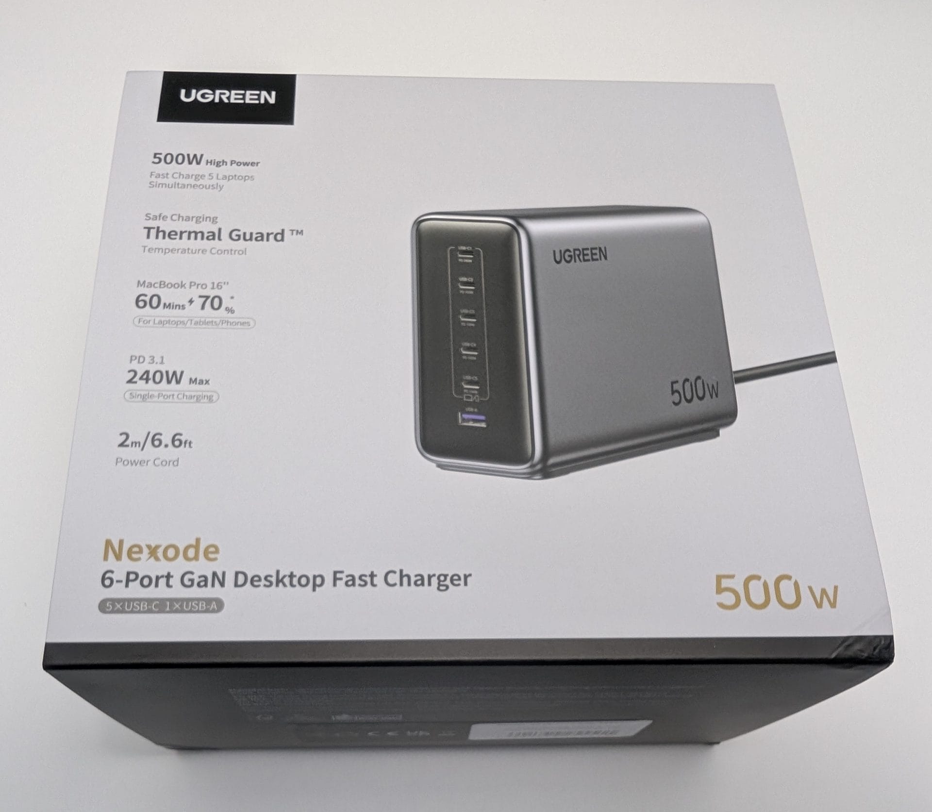 A box for the UGREEN Nexode 500W Charger, featuring a sleek, rectangular charger with multiple ports (5 USB-C, 1 USB-A). The packaging highlights "500W High Power," "Fast Charge 5 Laptops Simultaneously," and "Thermal Guard™" technology. It also notes compatibility with a MacBook Pro 16", charging to 60% in 70 minutes, supports PD 3.1, delivers 240W maximum single-port charging, and includes a 2-metre 6.6-foot power cord. The design is modern with a grey finish.