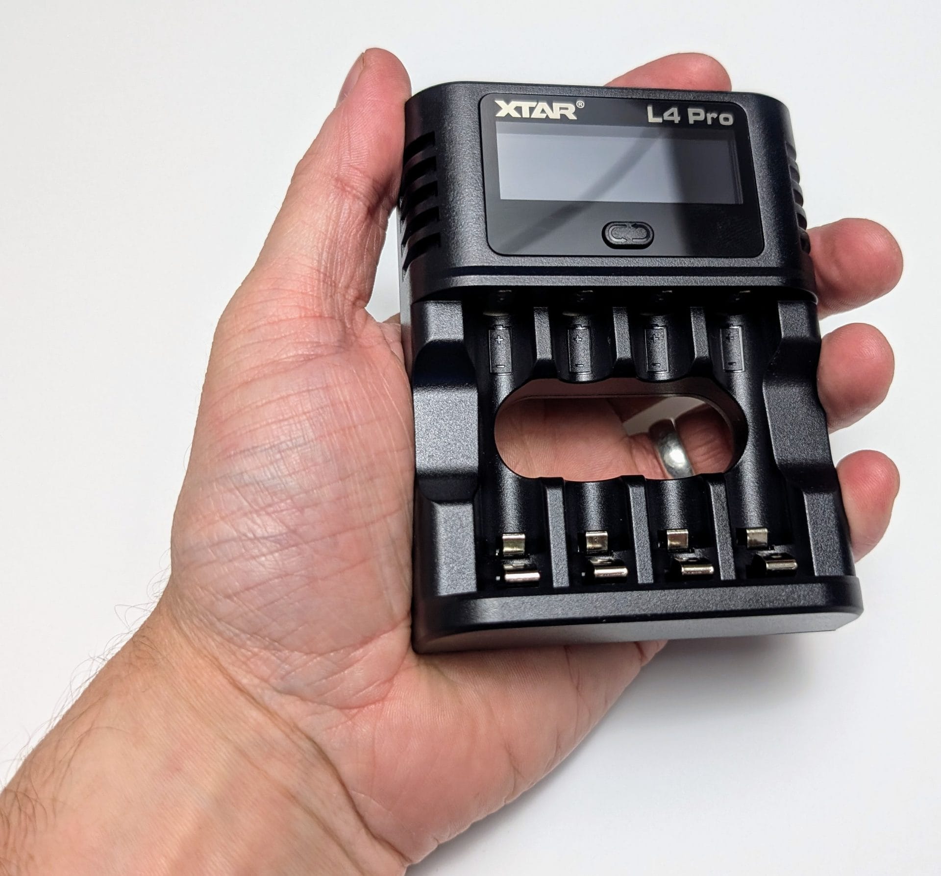 XTAR L4 Pro Battery Charger A hand holding the XTAR L4 Pro Smart Battery Charger, a compact black device with a digital display and four battery slots, set against a white background.