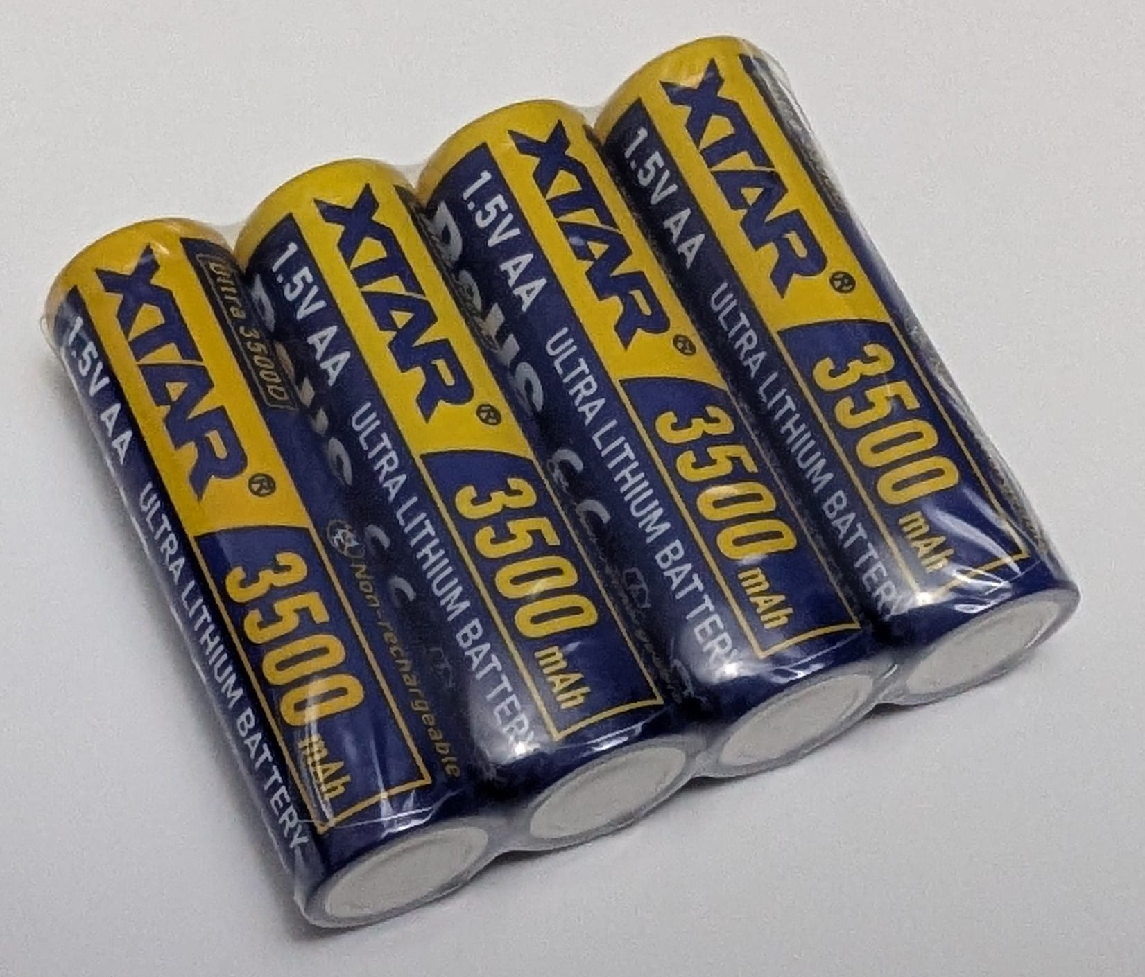 XTAR Ultra3500D AA Lithium 3500mAh Non-Rechargeable Batteries Four XTAR Ultra3500D AA lithium non-rechargeable batteries, each wrapped in clear plastic. The batteries are yellow with blue and white text, labeled "XTAR Ultra Lithium Battery," "1.5V AA," and "3500 mAh." They are arranged in a row on a plain, light grey surface.