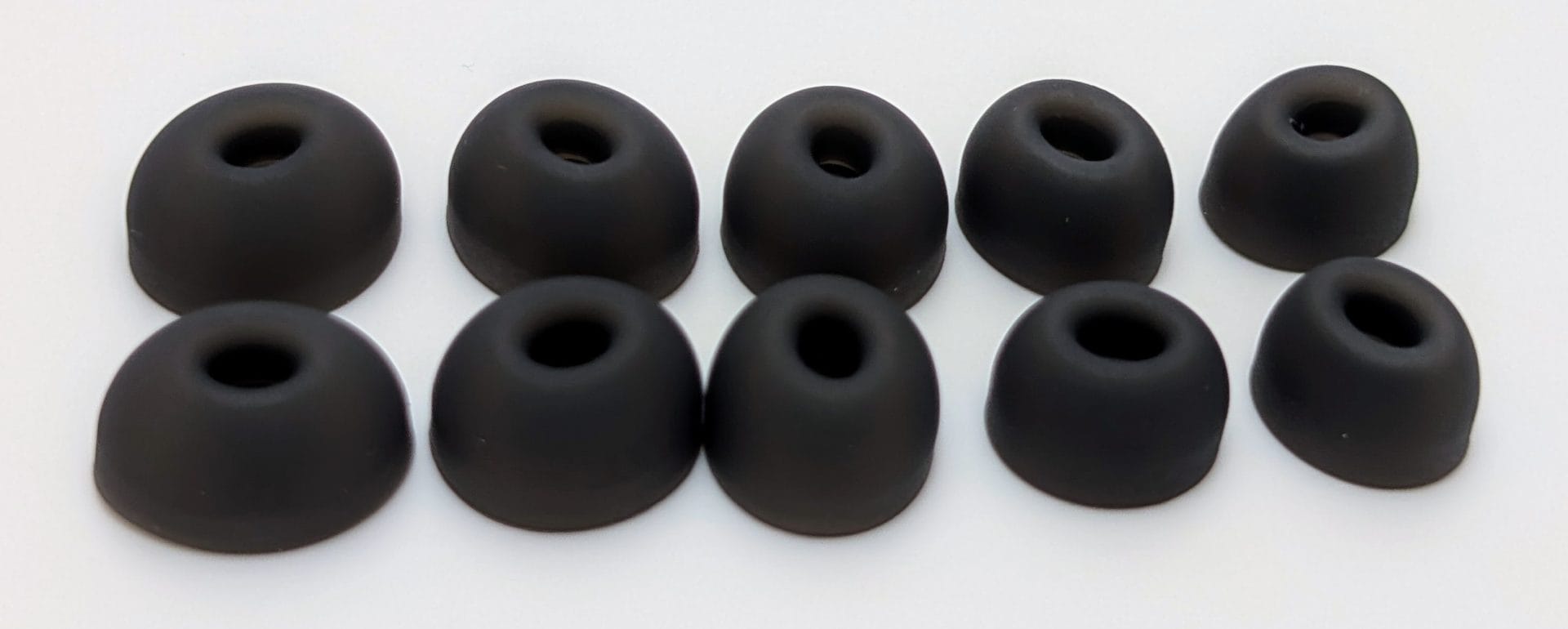 Image of ten black ear tips of varying sizes arranged in two rows on a white background, likely included as accessories for earbuds.
