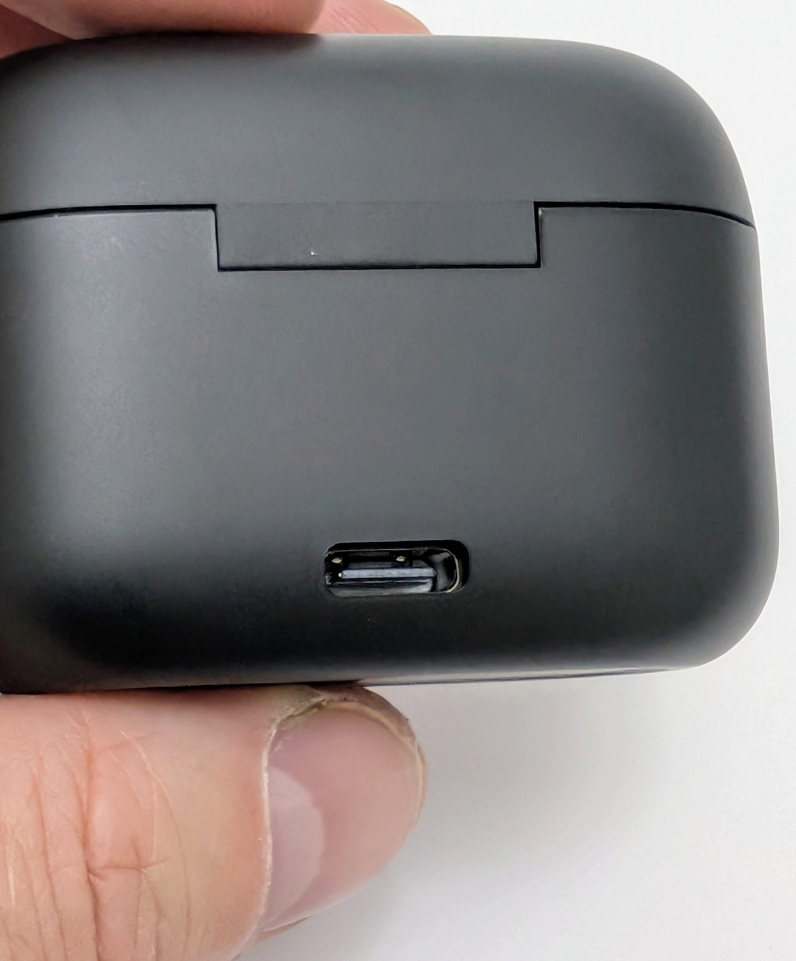 Image of a hand holding a closed black TOZO T20 wireless earbuds charging case, showing the USB-C charging port on the back against a white background.