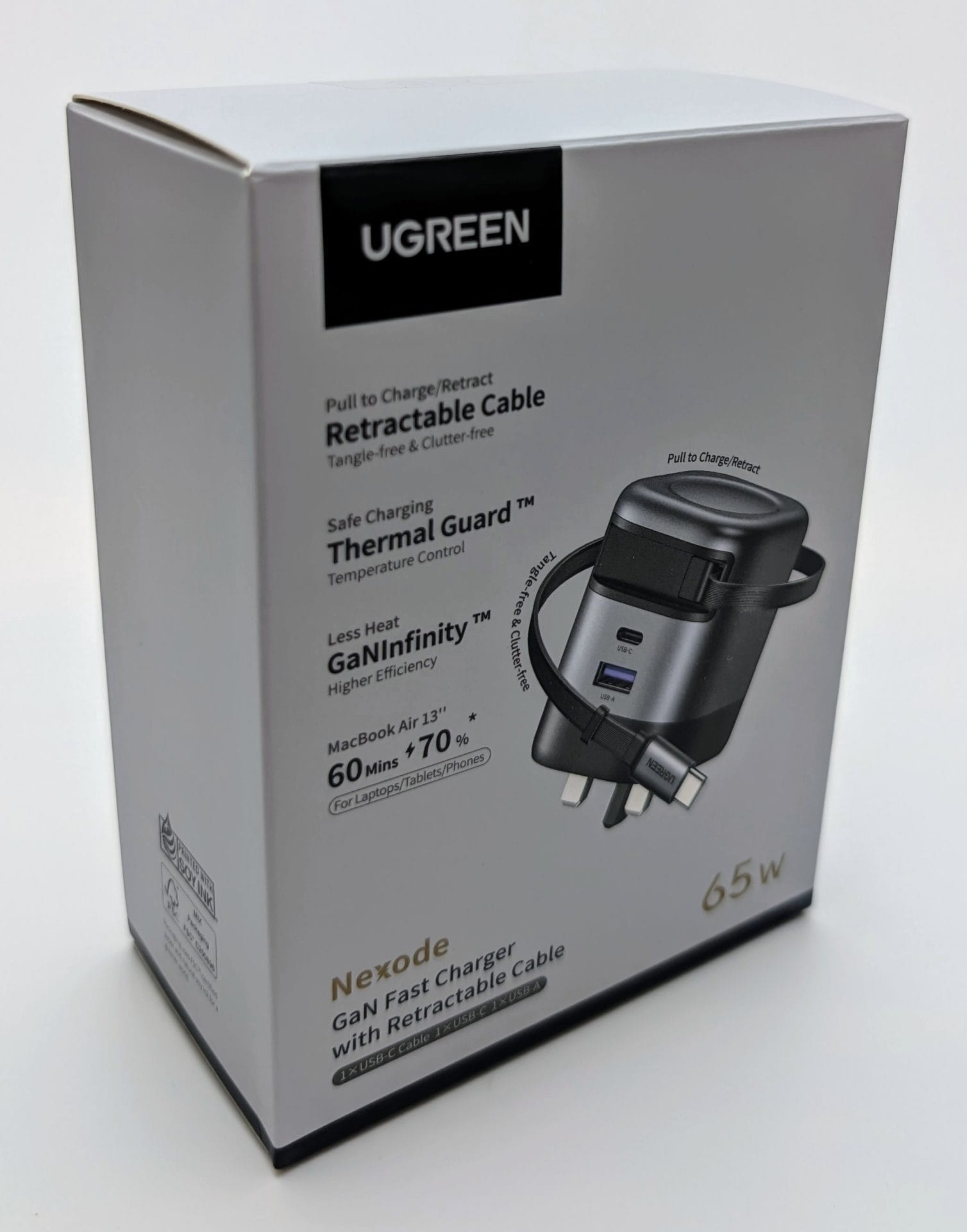 UGREEN Nexode 65W Charger with Retractable USB-C Cable packaging box. The box features a sleek black and gray charger with a retractable cable, multiple ports (USB-C and USB-A), and a UK plug. Text highlights include "Safe Charging Guard TM" with Thermal Control, "GaNInfinity" for higher efficiency, and "MacBook Air 13" + 70% in 60 mins" for fast charging laptops, tablets, and phones. The brand logo "UGREEN" is prominently displayed on top.