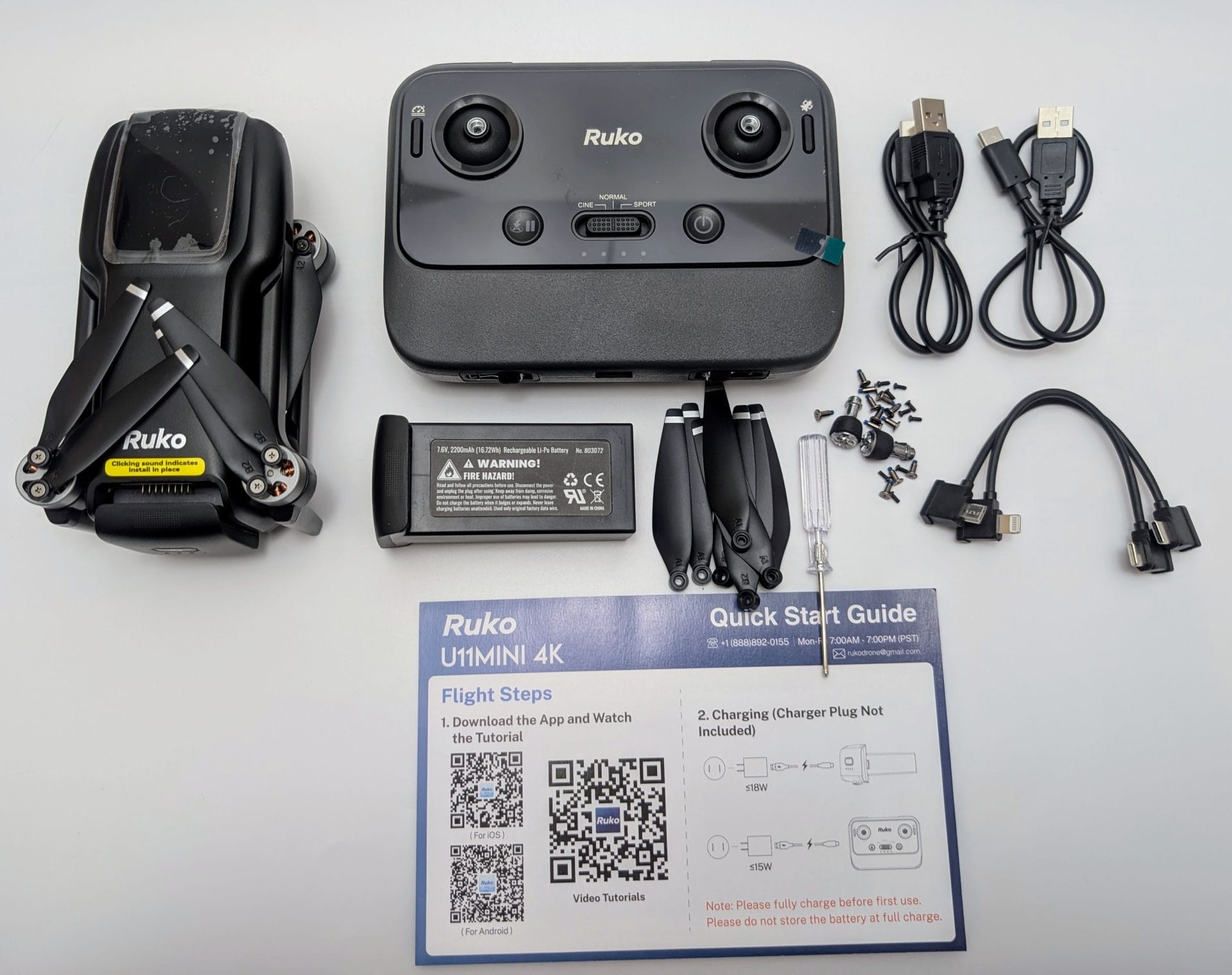 A layout of the Ruko U11MINI 4K Drone kit on a white background, including the black drone with visible propellers and a scratched lens, a black controller with joysticks and buttons labeled "Ruko," a rechargeable battery, spare propellers, screws, a screwdriver, USB cables with different connectors, and a quick start guide. The guide lists flight steps, charging instructions, and QR codes for tutorials, with a note to fully charge the battery before first use.