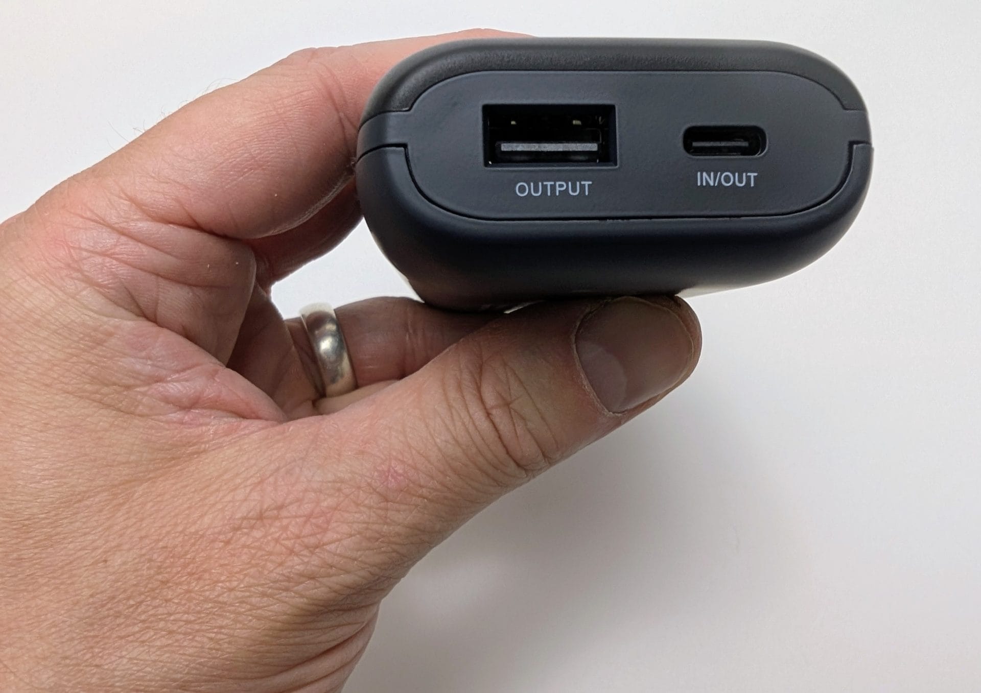 XTAR PB2SL V2 Alt text : A hand holding an XTAR PB2SL V2 power bank, showing its black exterior with a USB-A output port and a USB-C in/out port. The device is displayed against a plain white background, with a ring visible on the finger.